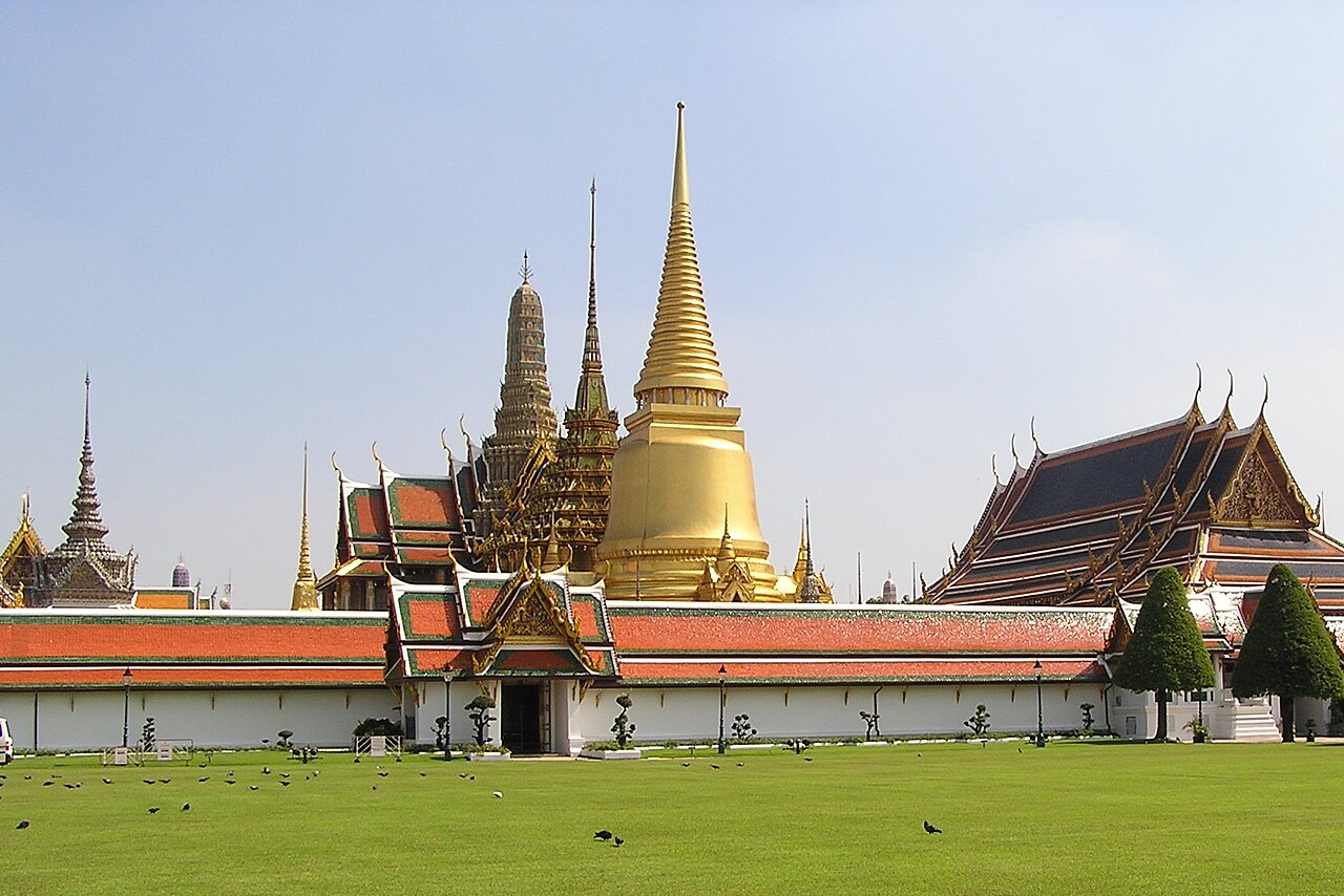 พระบรมมหาราชวังและวัดพระแก้ว กรุงเทพฯ — พระศรีรัตนเจดีย์สีทองและหลังคาวัดเหนือกำแพงขาว ใต้ฟ้าใส