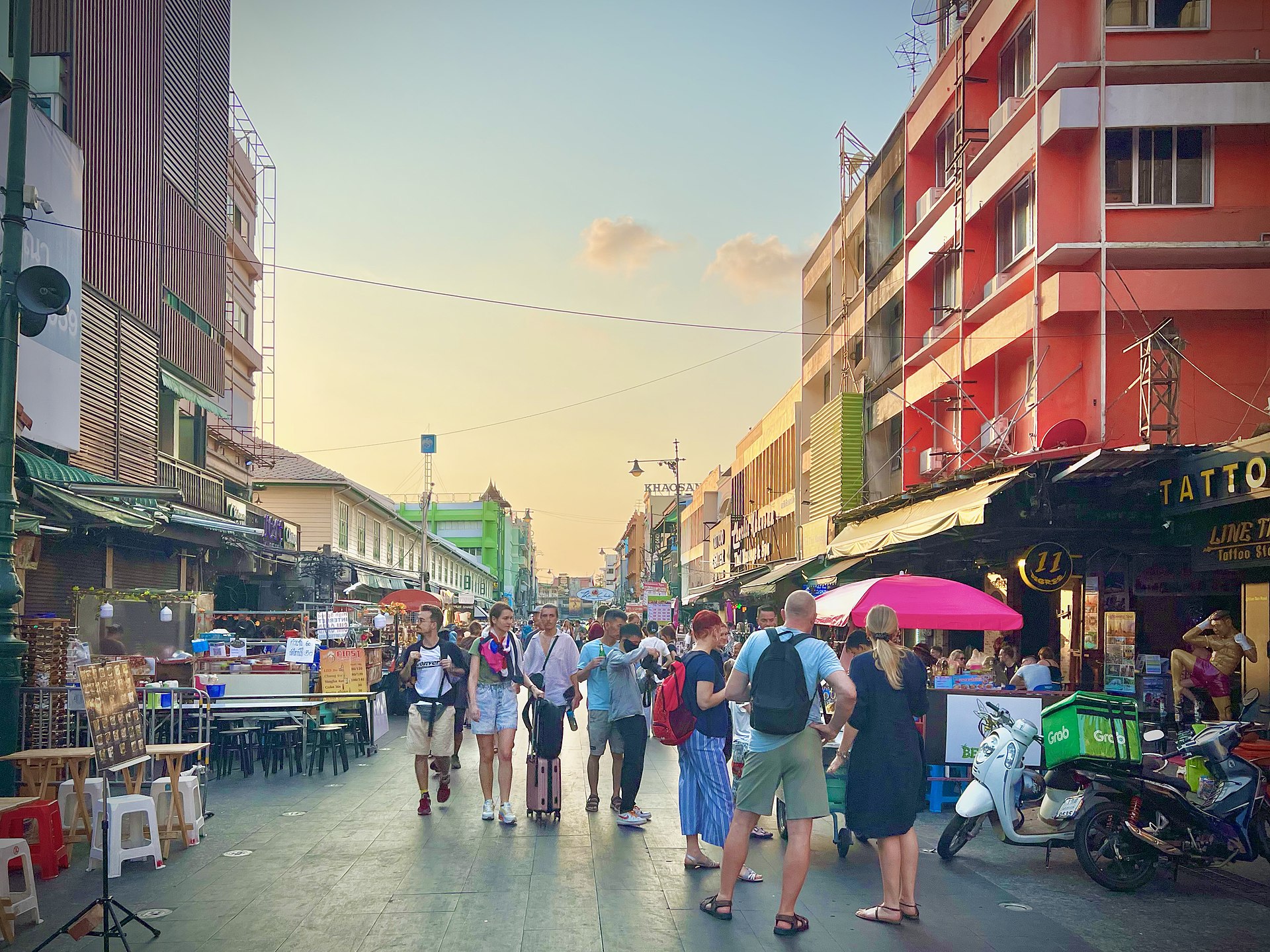 ถนนข้าวสาร กรุงเทพฯ — นักท่องเที่ยวเดินบนถนนช่วงเย็น ร้านรวงสองฝั่งและแสงแดดอ่อน