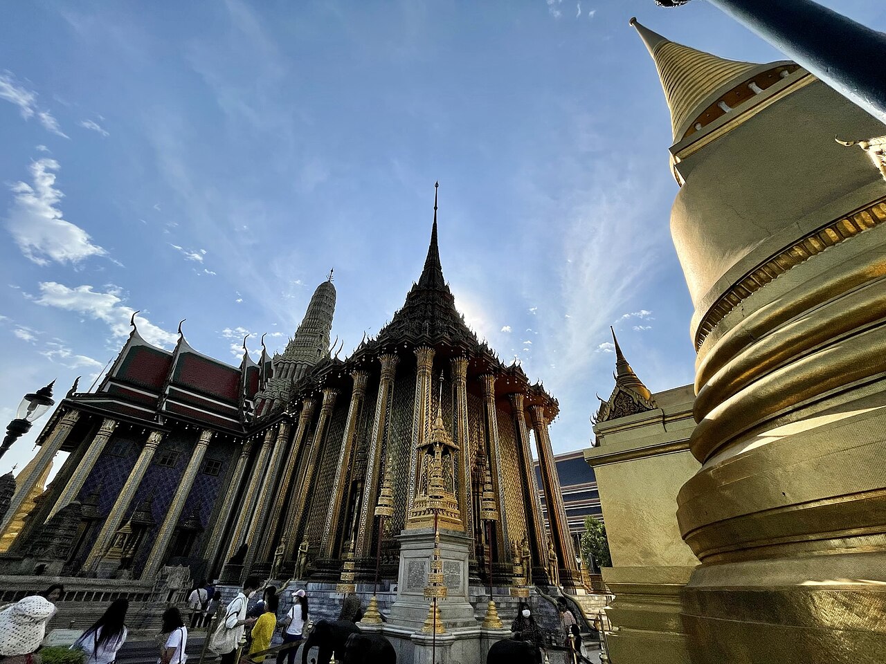 ปราสาทพระเทพบิดรและเจดีย์ทองในวัดพระแก้ว มุมมองแหงนขึ้นตัดกับท้องฟ้า เห็นเสาและยอดปราสาทประดับกระจกสีระยิบ