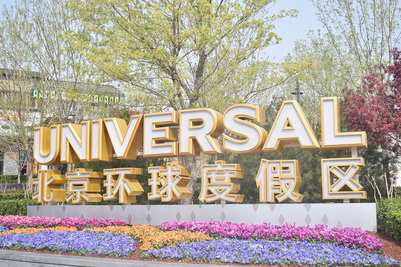 The golden UNIVERSAL 北京环球度假区 sign at the entrance to Universal Beijing Resort, with a bed of colourful flowers in front
