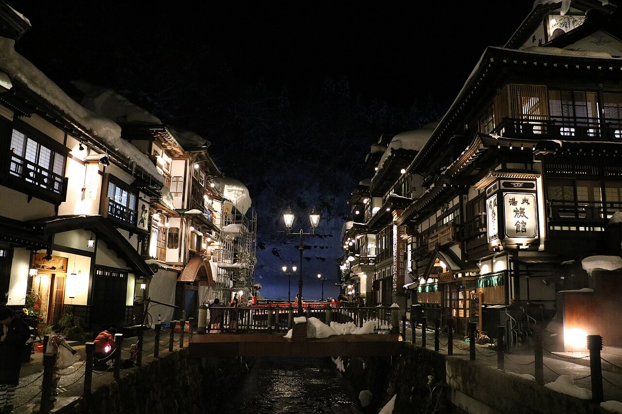 Ginzan Onsen หมู่บ้านออนเซนเรียวกังไม้สมัยไทโชริมลำธารยามค่ำคืนมีหิมะปกคลุม