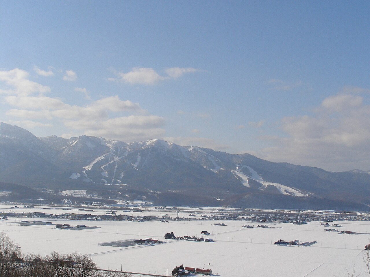 View of Furano ski runs on the mountainside in central Hokkaido above snowy fields