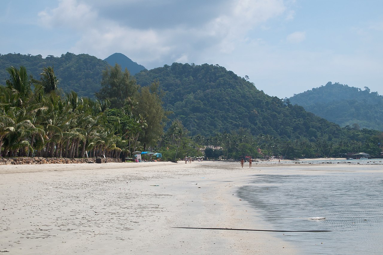 หาดคลองพร้าว เกาะช้าง — ทิวมะพร้าวริมหาดกับปากคลองและภูเขาของอุทยานแห่งชาติหมู่เกาะช้าง