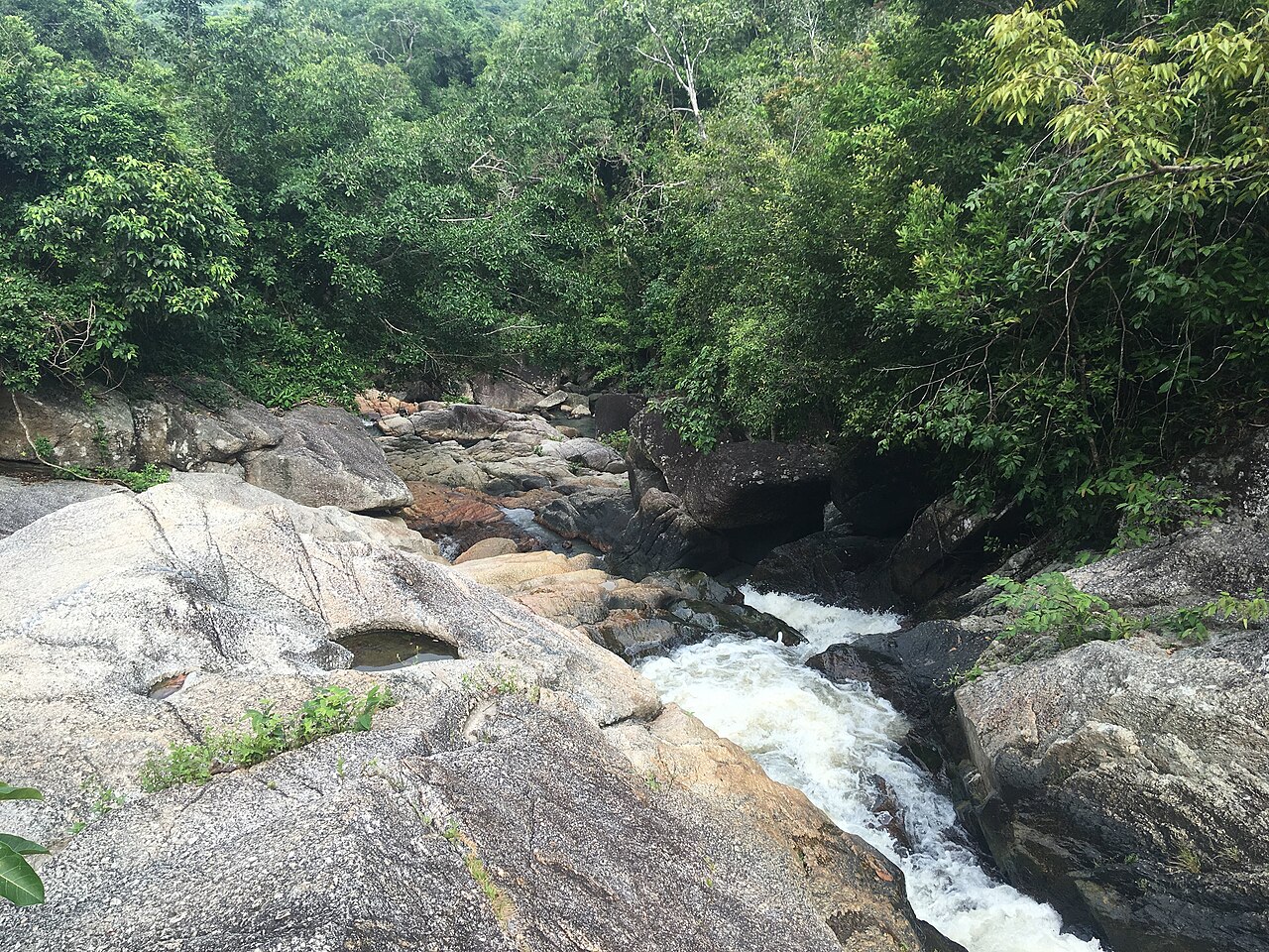 Than Sadet waterfall on Koh Phangan, water running over granite boulders in green jungle