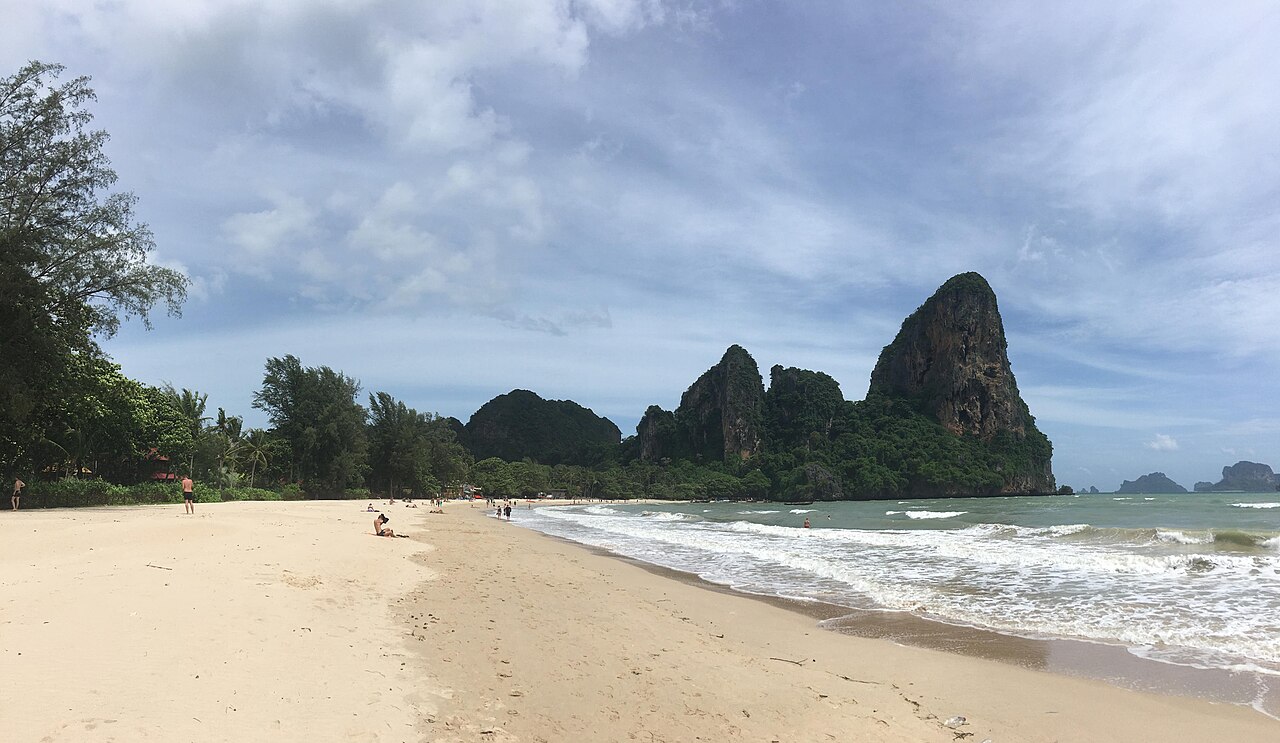 Railay Beach Krabi — a long arc of white sand backed by sheer limestone cliffs and clear sea, a peninsula reachable only by boat