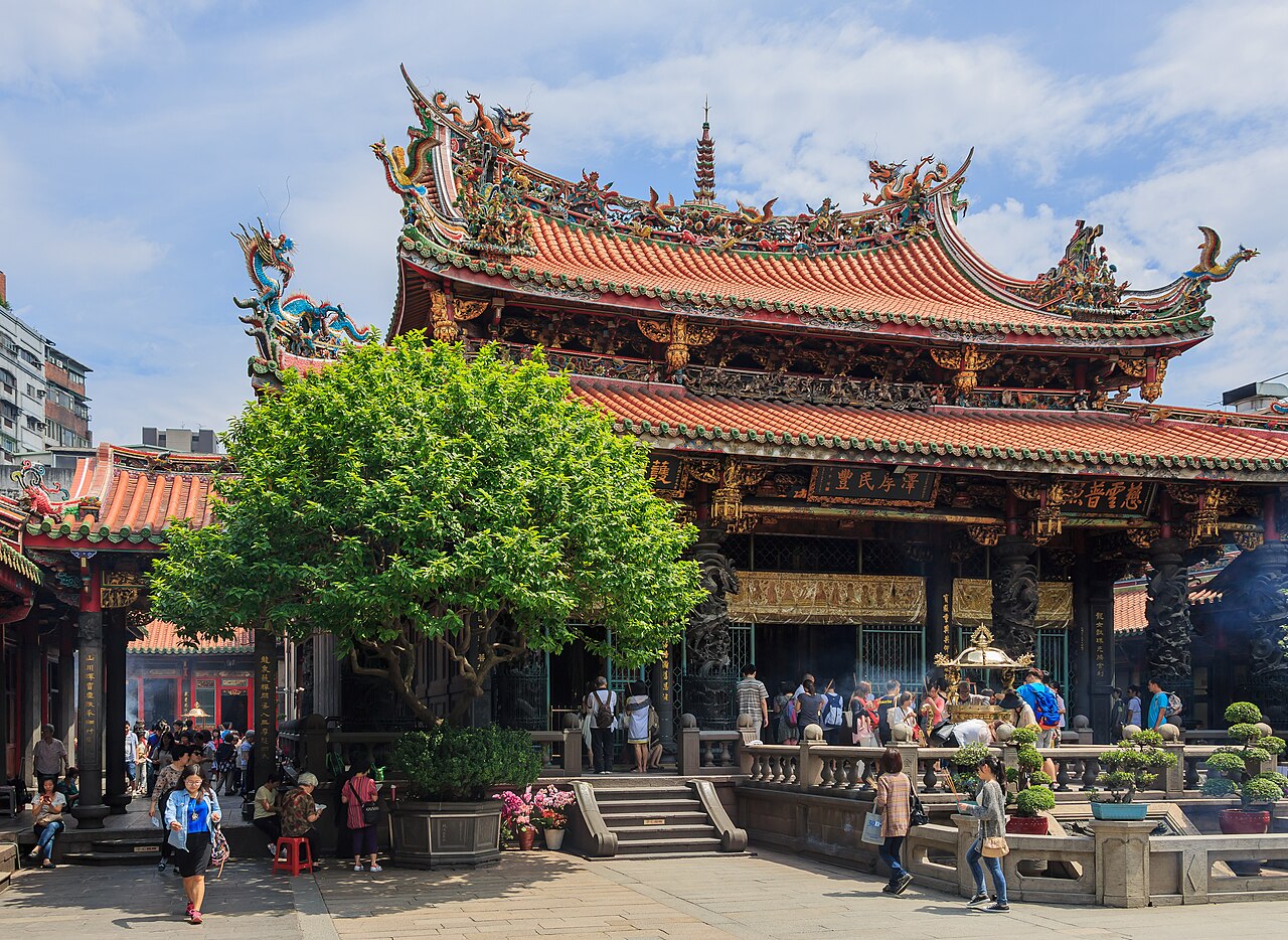 Taiwan temple courtyard with ornate carved roofline, stone pillars and incense burners