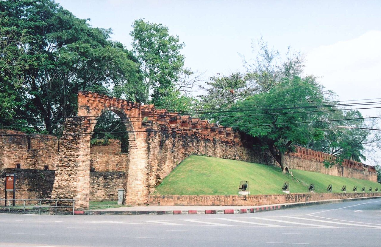 กำแพงเมืองเก่านครศรีธรรมราช — กำแพงอิฐและประตูโค้งของเมืองโบราณ ริมถนน มีคูเมืองและสนามหญ้า