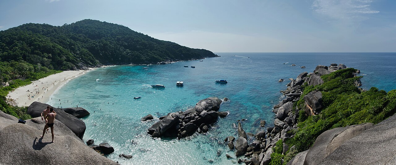 The Similan Islands — a clear turquoise bay with white sand, large granite boulders and tour boats anchored in the bay