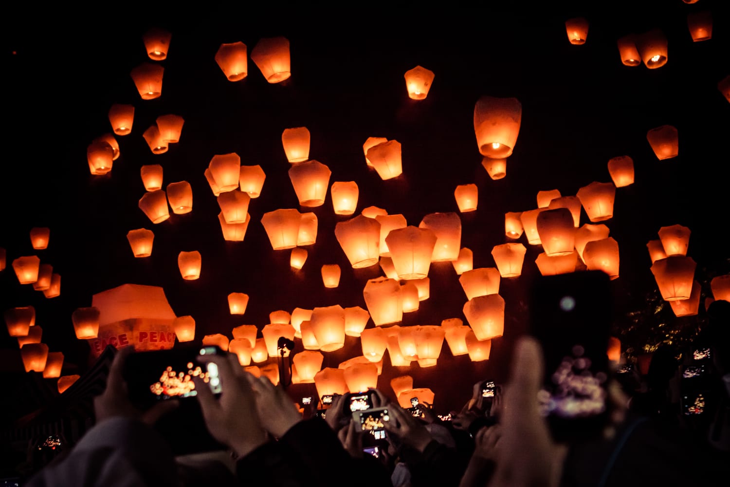 A couple releasing a glowing red sky lantern at Shifen Old Street railway track