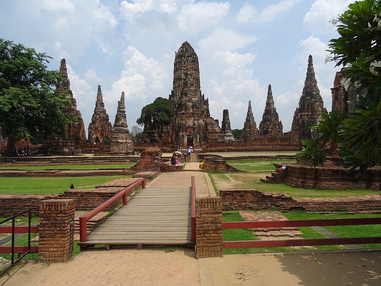ทางเดินเข้าวัดไชยวัฒนาราม อยุธยา — สะพานไม้นำสายตาสู่ปรางค์ประธานและเจดีย์ทรงปรางค์รอบวัด