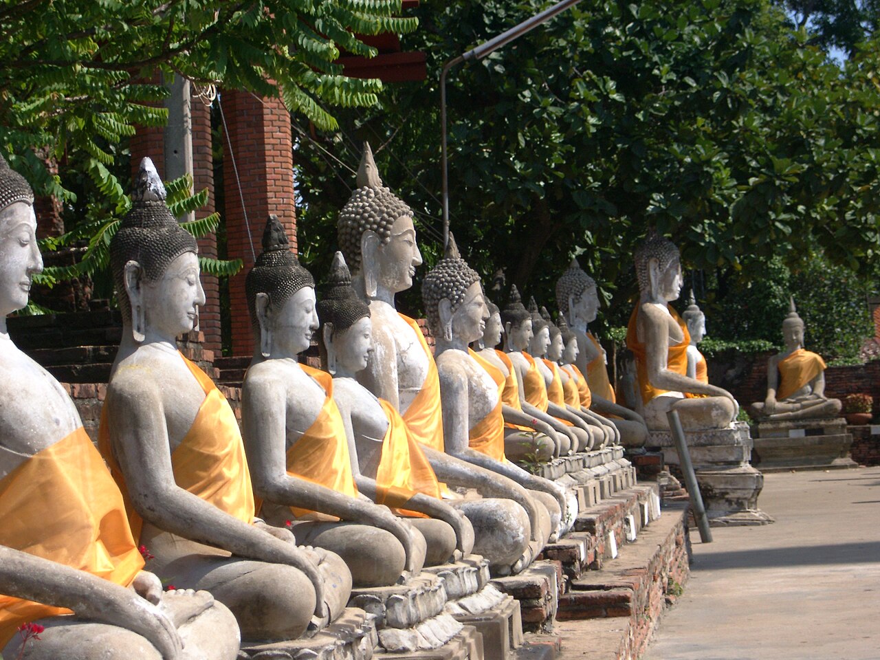แถวพระพุทธรูปนั่งห่มผ้าจีวรเหลืองเรียงต่อกันรอบระเบียงคดวัดใหญ่ชัยมงคล อยุธยา