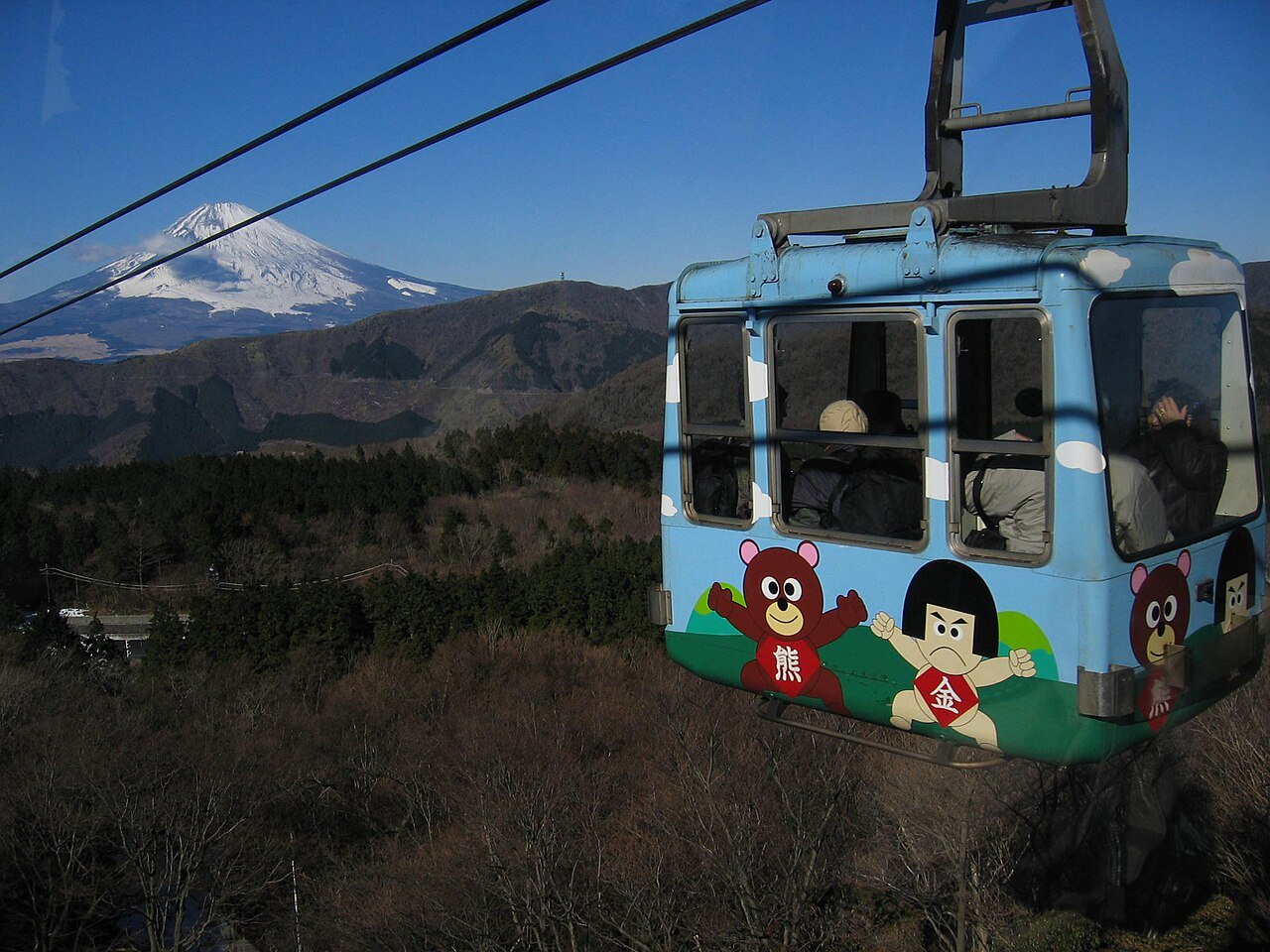 A Hakone Ropeway gondola gliding over the Owakudani valley, where white sulphurous steam rises from cracks in the grey volcanic ground