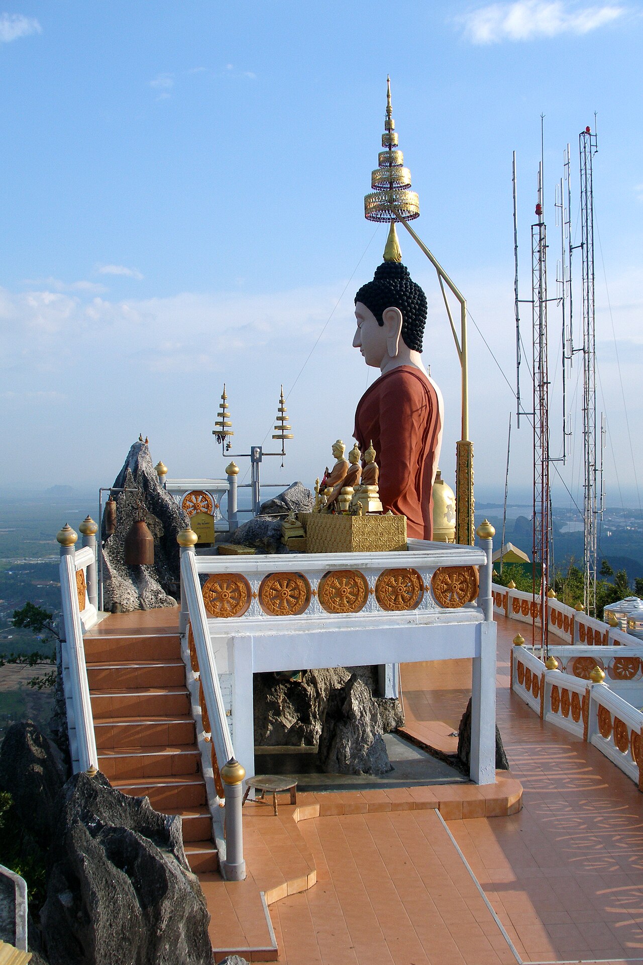 The summit platform at Tiger Cave Temple, Krabi, with a Buddha and stupa overlooking the plains below