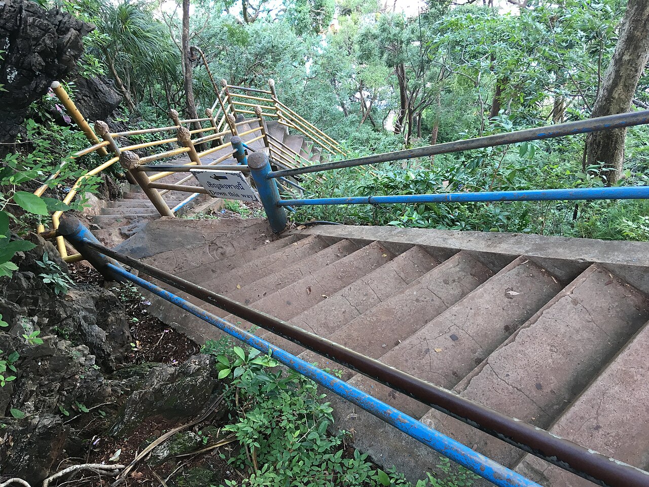 The steep concrete staircase at Tiger Cave Temple, Krabi, climbing through the forest with handrails on both sides