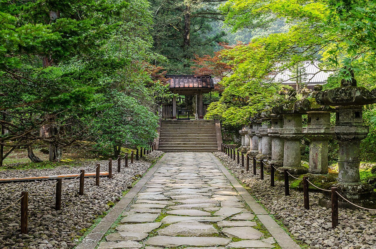 Rinnoji Temple, Nikko — a stone path lined with stone lanterns leading to a hall in green forest, a UNESCO site
