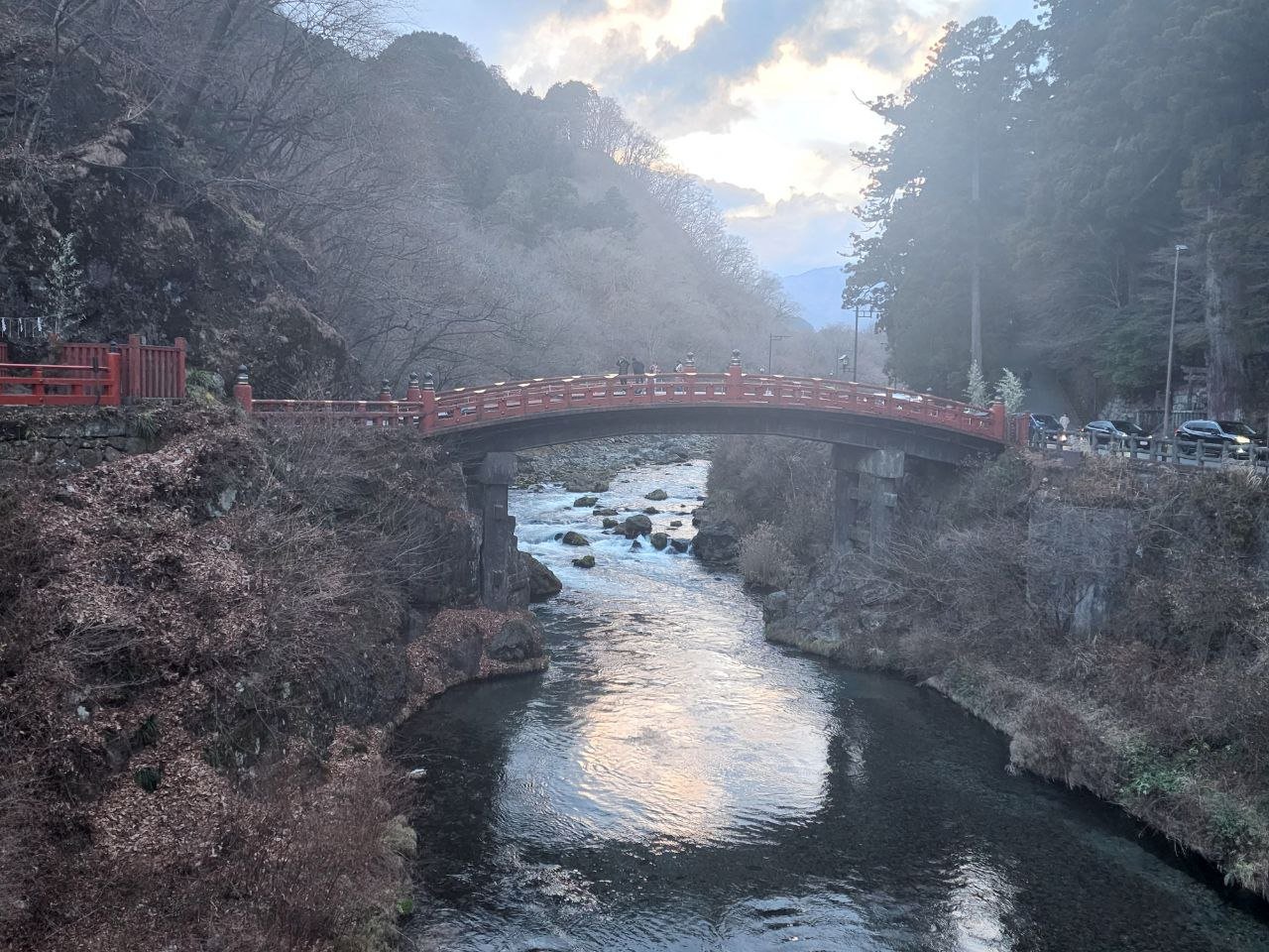 Shinkyo Bridge, Nikko — an arched vermilion wooden bridge over the Daiya River with mountains and forest behind