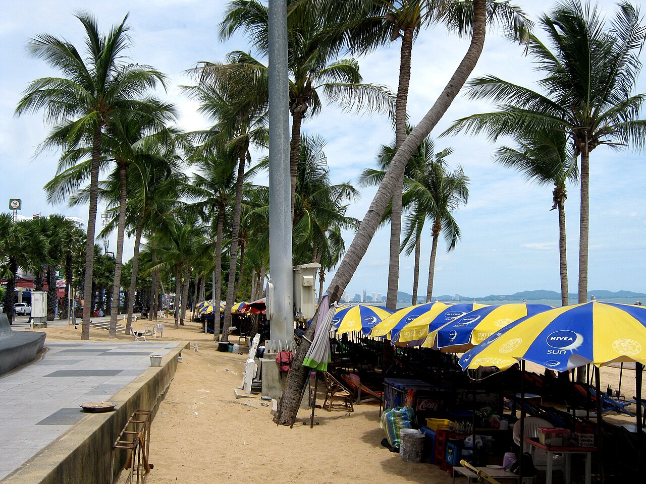 หาดพัทยา — หาดทรายกลางเมืองริมถนนเลียบชายหาด มีต้นมะพร้าวเรียงราย ร่มเตียงผ้าใบ และทะเลอ่าวไทย