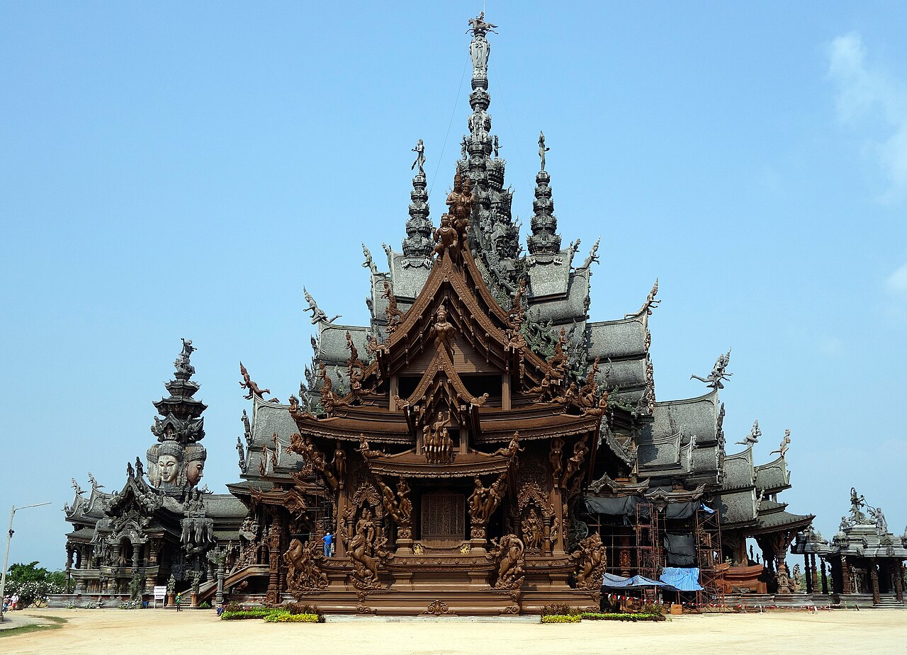 ปราสาทสัจธรรม พัทยา — วิหารไม้สักสีน้ำตาลแกะสลักลวดลายทั้งหลัง ยอดแหลมสูงหลายชั้น ตั้งริมทะเลแหลมราชเวช
