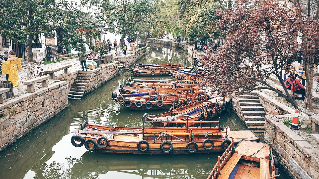 Canal in Tongli water town near Suzhou — wooden rowing boats moored along the water, old houses and stone steps lining both banks