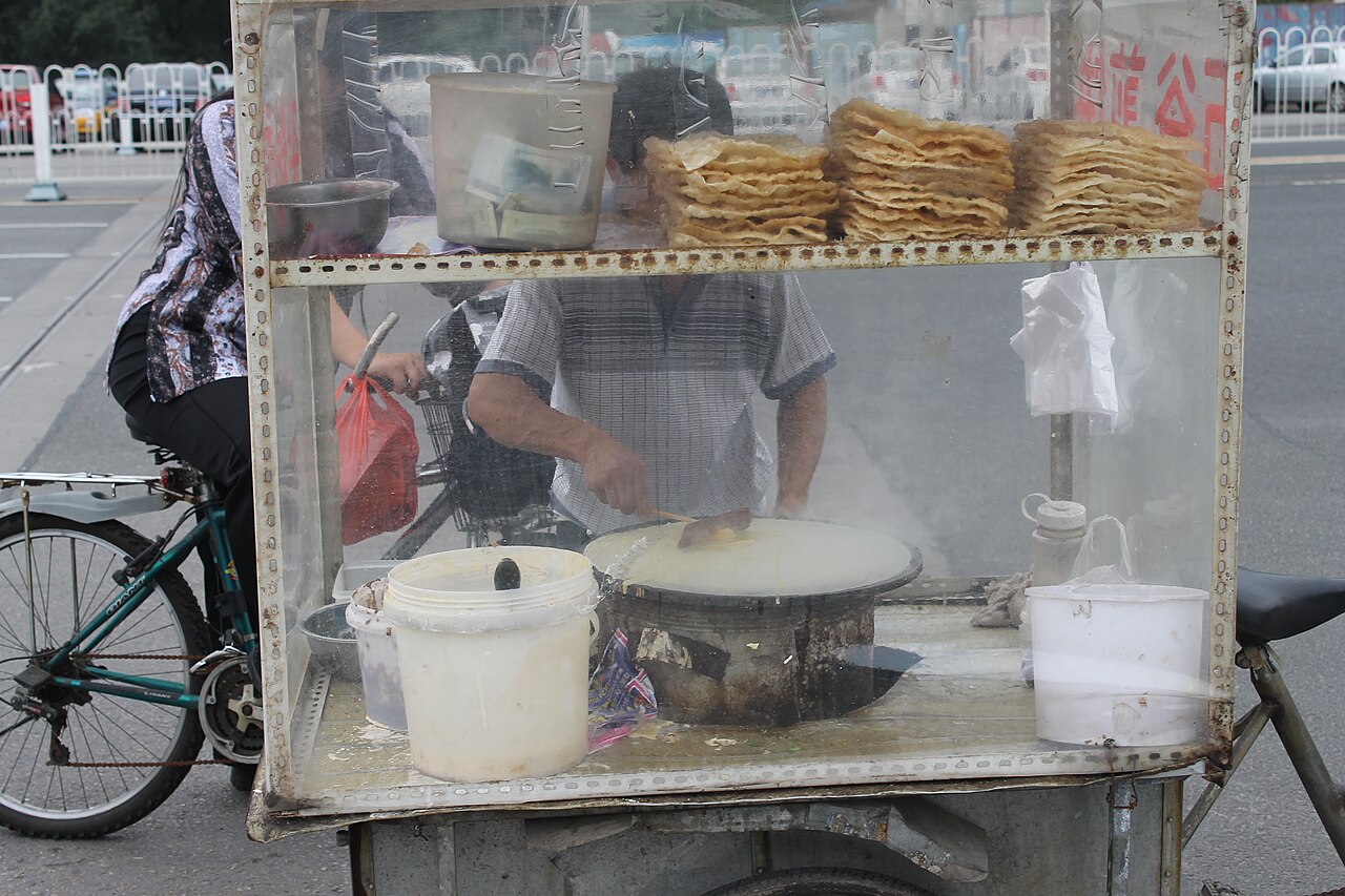 Beijing jianbing — a thin savoury egg crepe brushed with sauce and folded around a crisp cracker, street breakfast