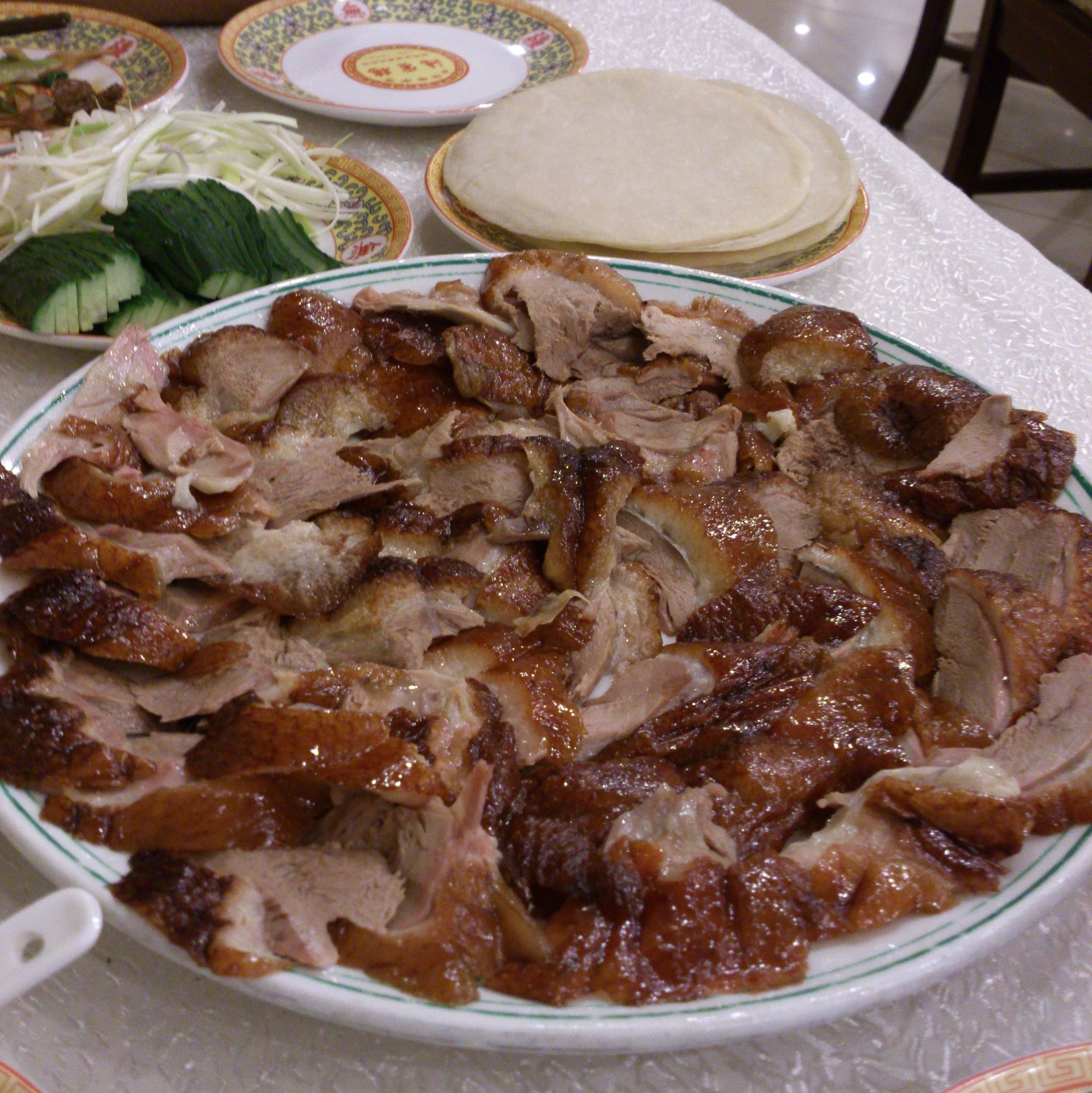 Peking duck — crisp golden-brown roast duck sliced thin, served with thin pancakes, spring onion and bean sauce