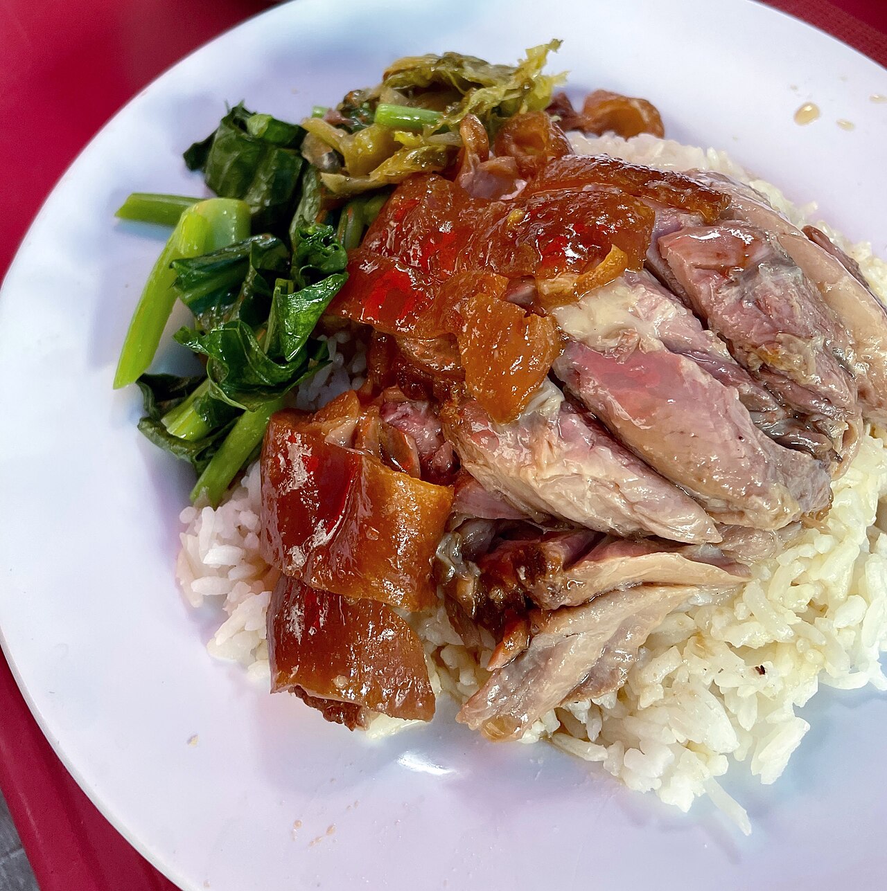 ข้าวขาหมูจานหนึ่ง ขาหมูตุ๋นนุ่มหนังเป็นวุ้นราดน้ำพะโล้บนข้าวสวย เสิร์ฟคู่ผักกาดดองและผักคะน้าลวก