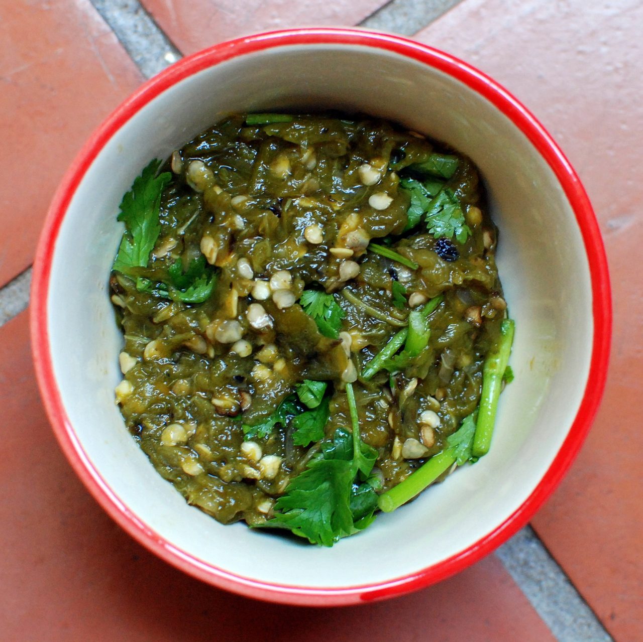 Nam prik num — a soft green roasted-chilli dip in a ceramic bowl, topped with coriander
