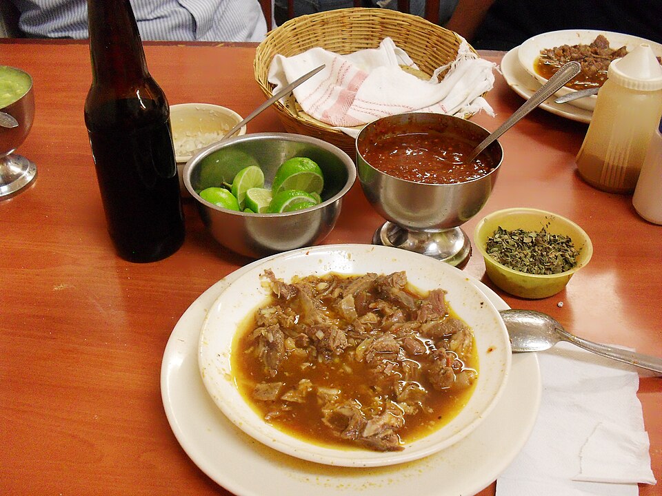 Birria deep red meat stew with tortillas and dipping broth