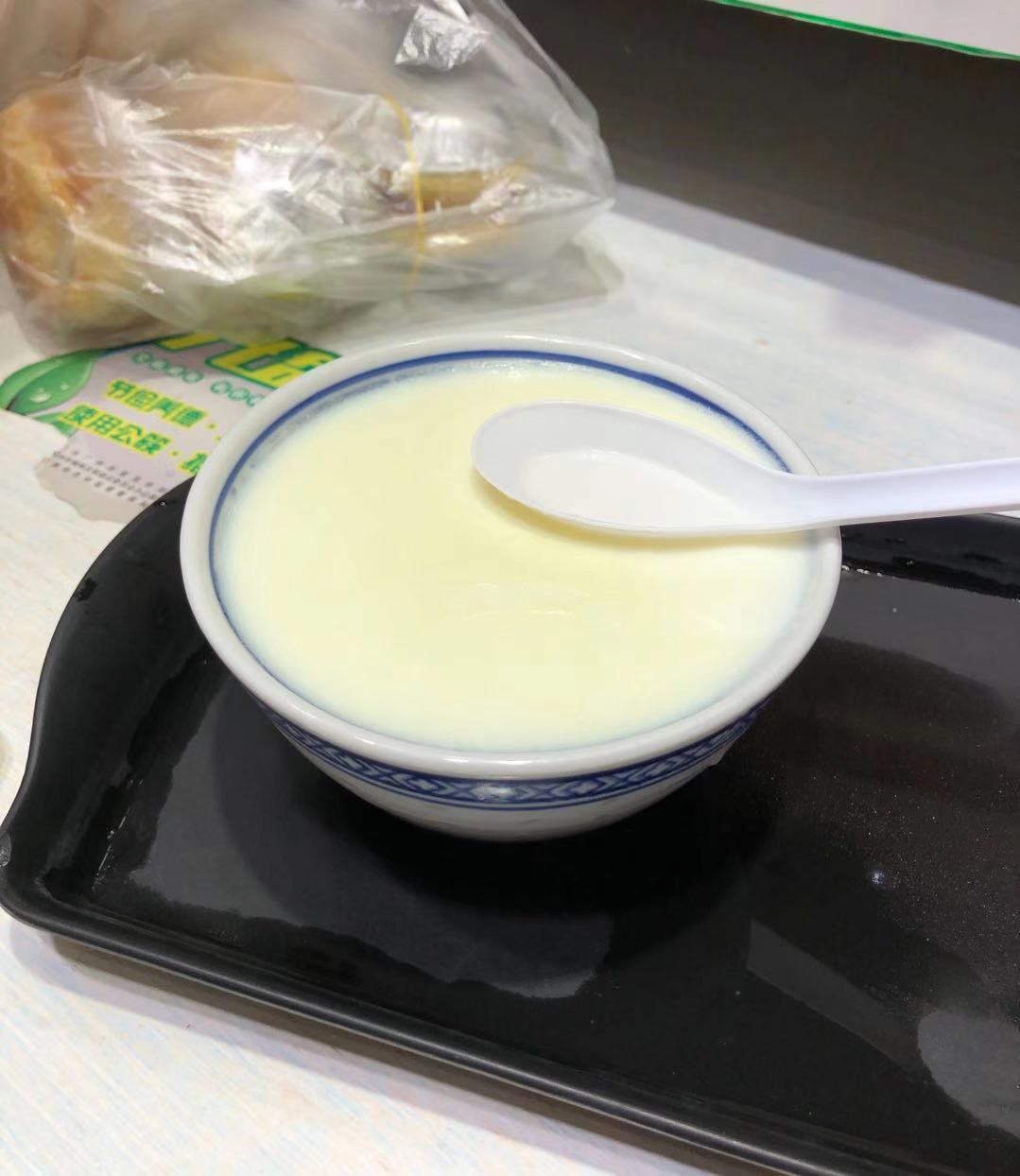 Double-skin milk (双皮奶) Cantonese dessert in a blue-rimmed porcelain bowl, the milk custard smooth and cream-coloured, served with a spoon