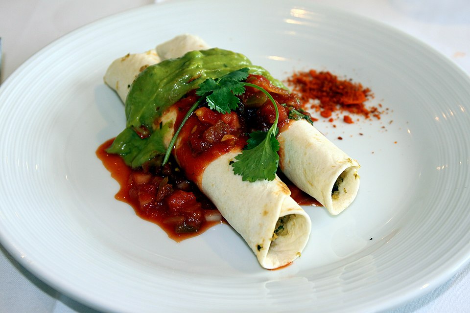 Tex-Mex enchiladas topped with sauce and cheese on a plate