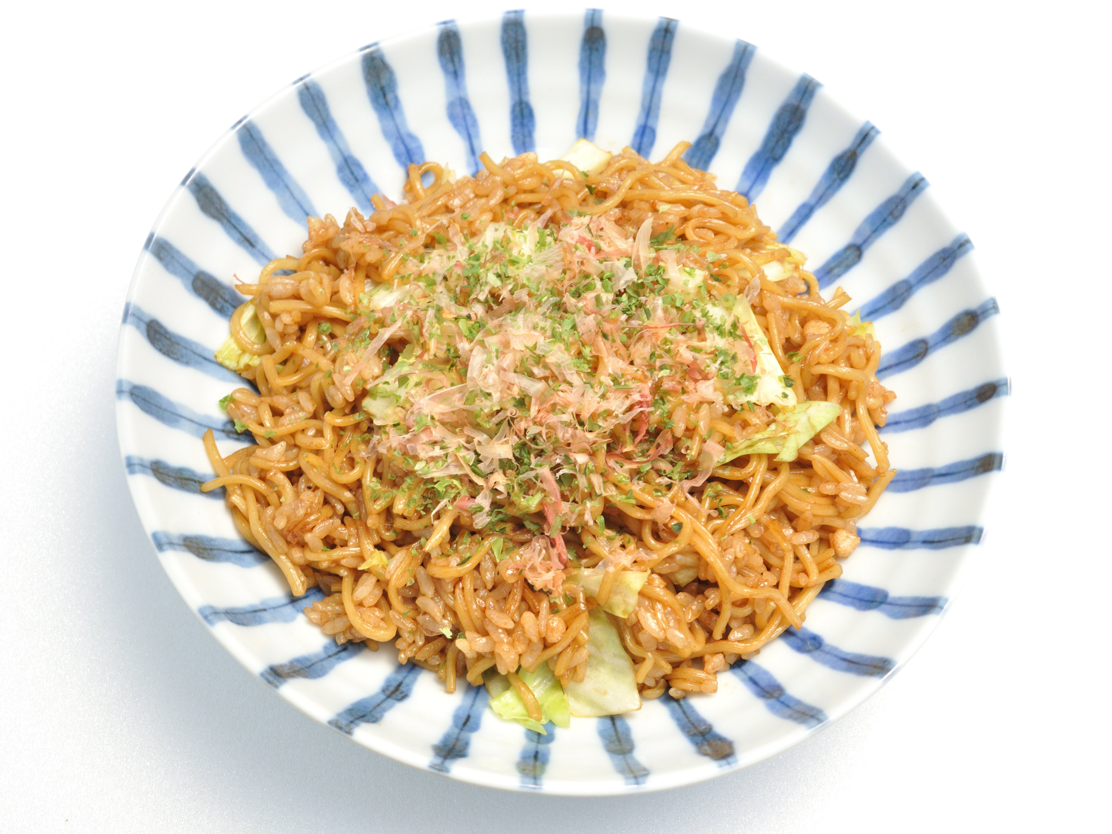 Sobameshi in a blue-and-white striped bowl — stir-fried yakisoba noodles mixed with rice in dark savoury sauce, topped with bonito flakes and spring onion