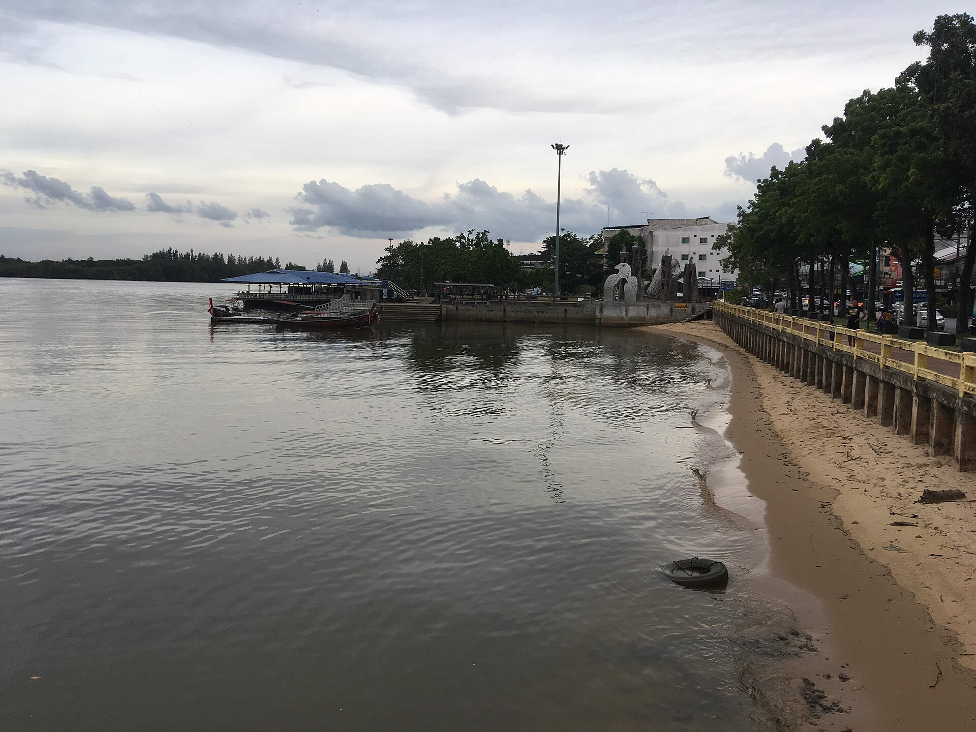 The Krabi riverside in town, longtail boats moored by the bank and a riverside walkway — the area with calm riverside cafés