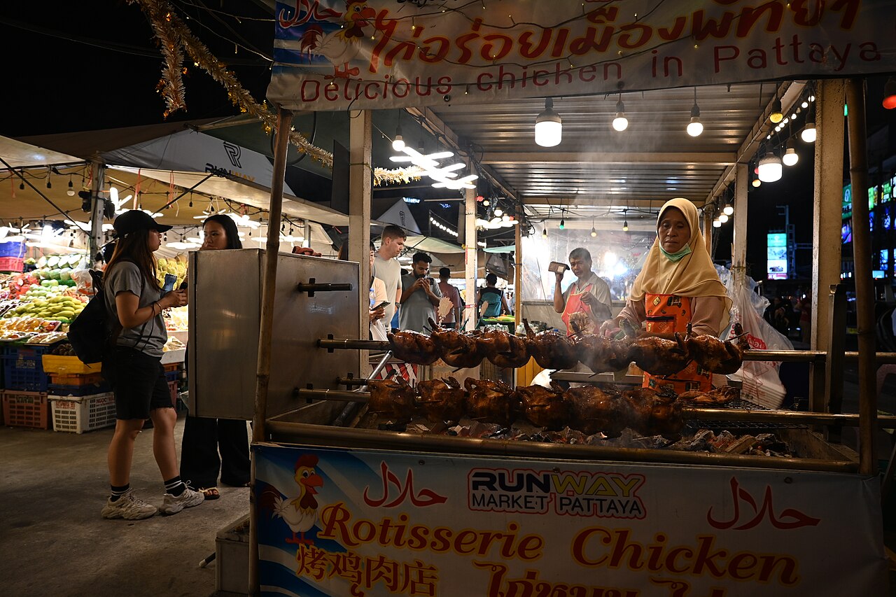 แผงไก่ย่างในตลาดกลางคืนพัทยา แม่ค้าดูแลเตาย่างไก่ขณะคนเดินเลือกซื้อ