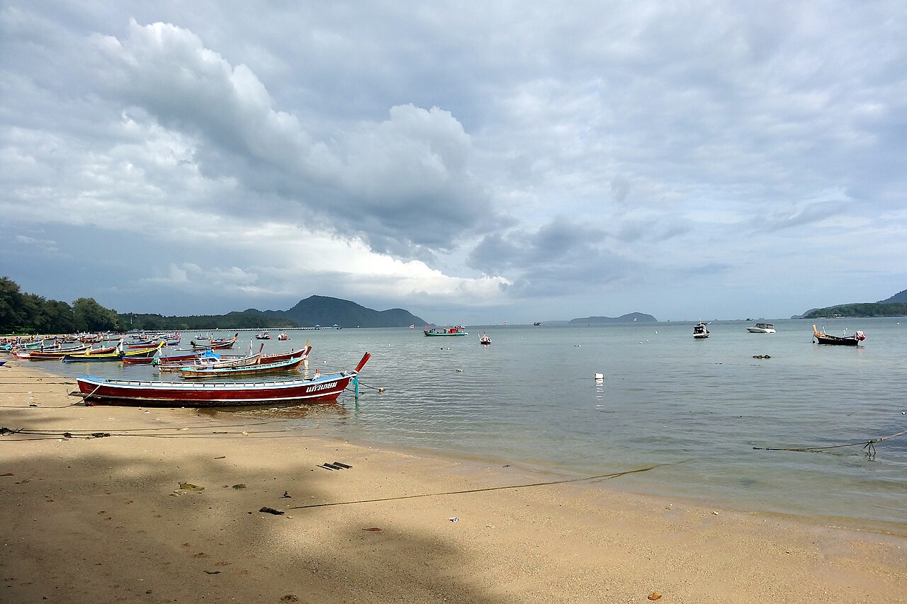 Rawai Beach in Phuket, a shoreline with fishing boats under a tropical sky — the island's best-known pick-your-own seafront seafood area