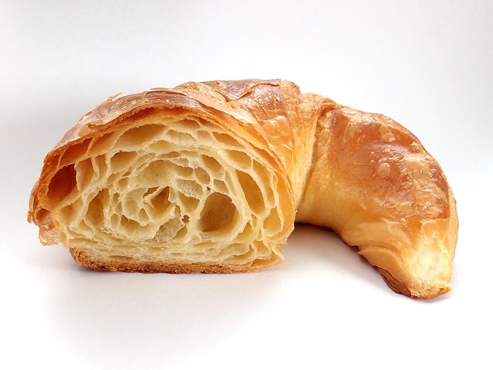 A buttery baked croissant cut in half showing the layered interior