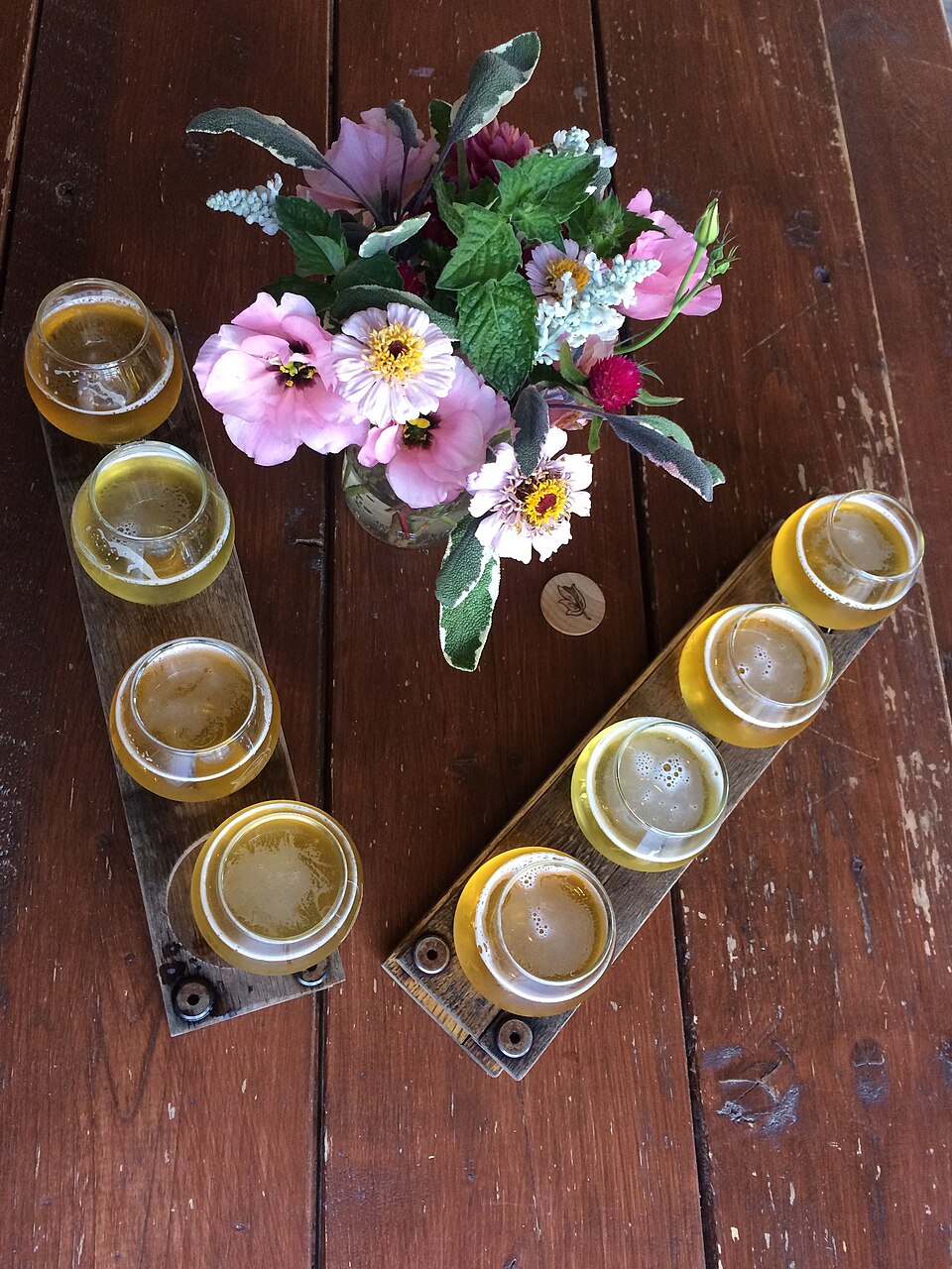 A flight of several craft beers lined up on a wooden tray