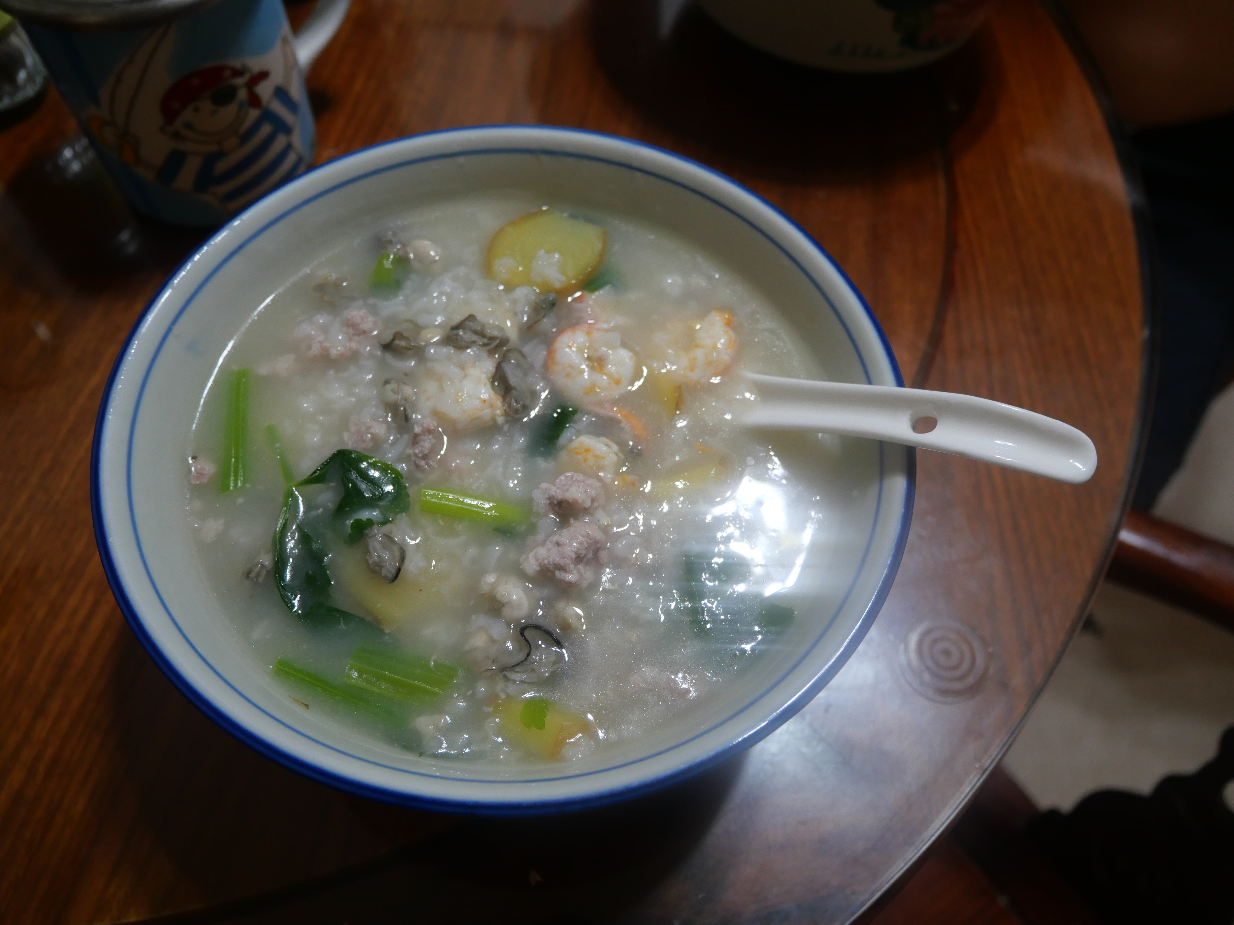 โจ๊กทะเลแต้จิ๋วในชาม ใส่กุ้ง หอยนางรม หมูสับ และผักใบเขียว เมล็ดข้าวยังเป็นตัวในน้ำซุปข้น