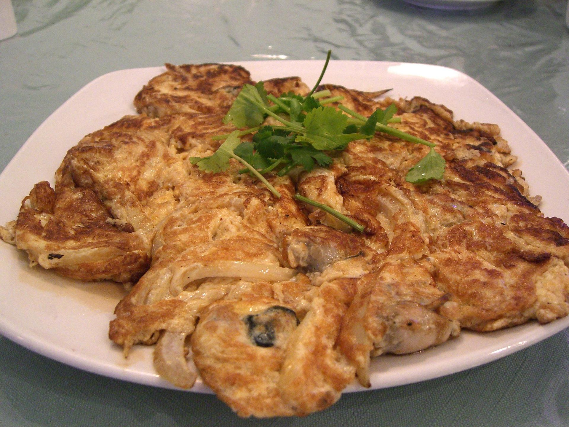 Oyster omelette, a golden crisp egg-and-starch pancake studded with plump oysters and topped with coriander