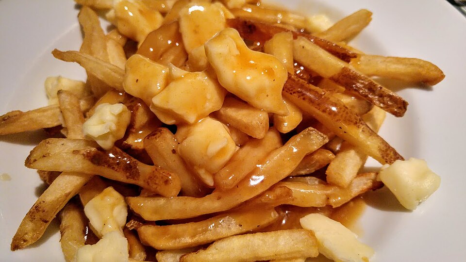 Poutine of french fries topped with gravy and white cheese curds on a plate