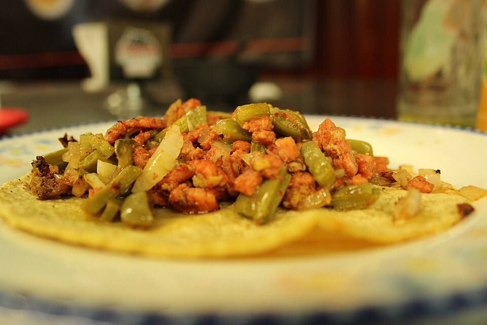 Several Mexican tacos on a plate with lime and salsa