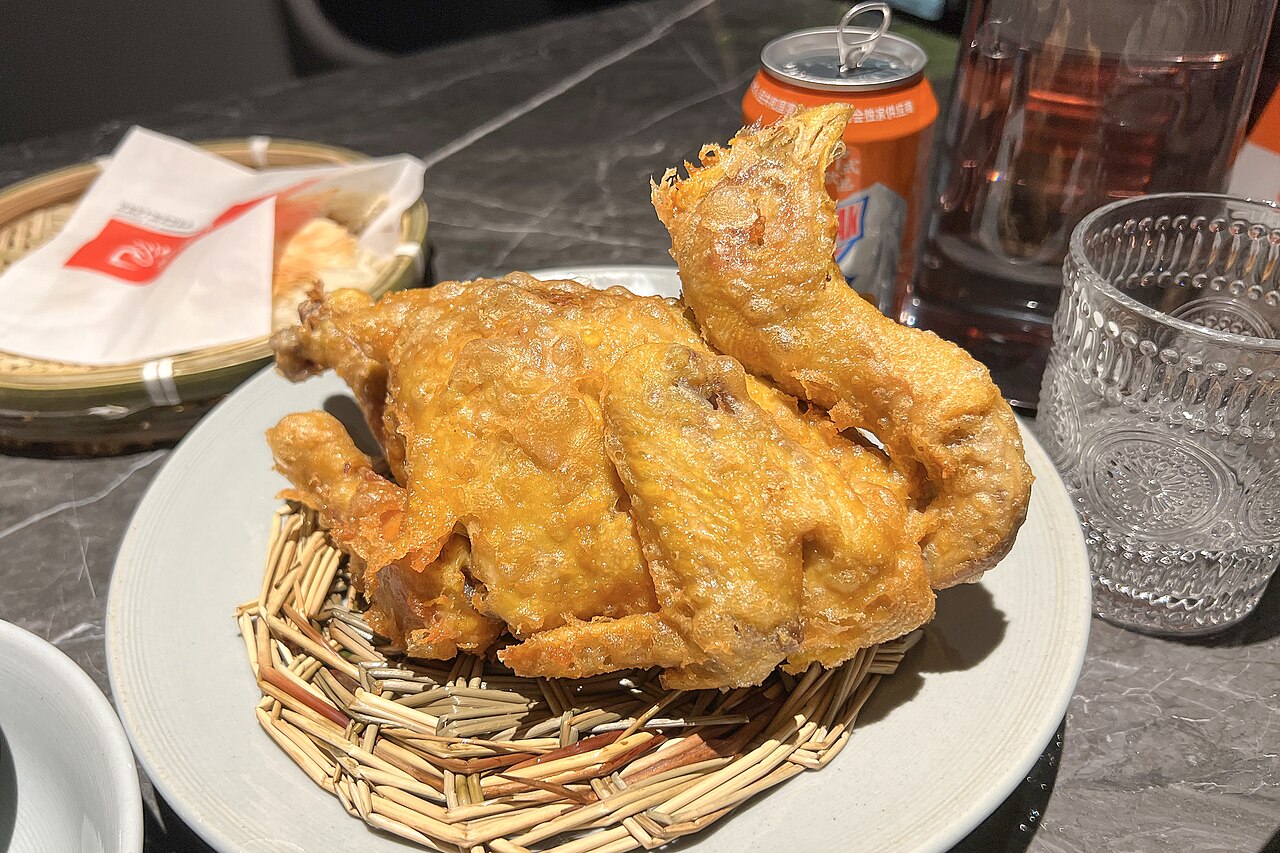 ไก่น้ำเต้า หูหลูจี ไก่ทั้งตัวทอดหนังกรอบสีทองมัดเป็นรูปน้ำเต้า วางในตะกร้าสานบนจาน