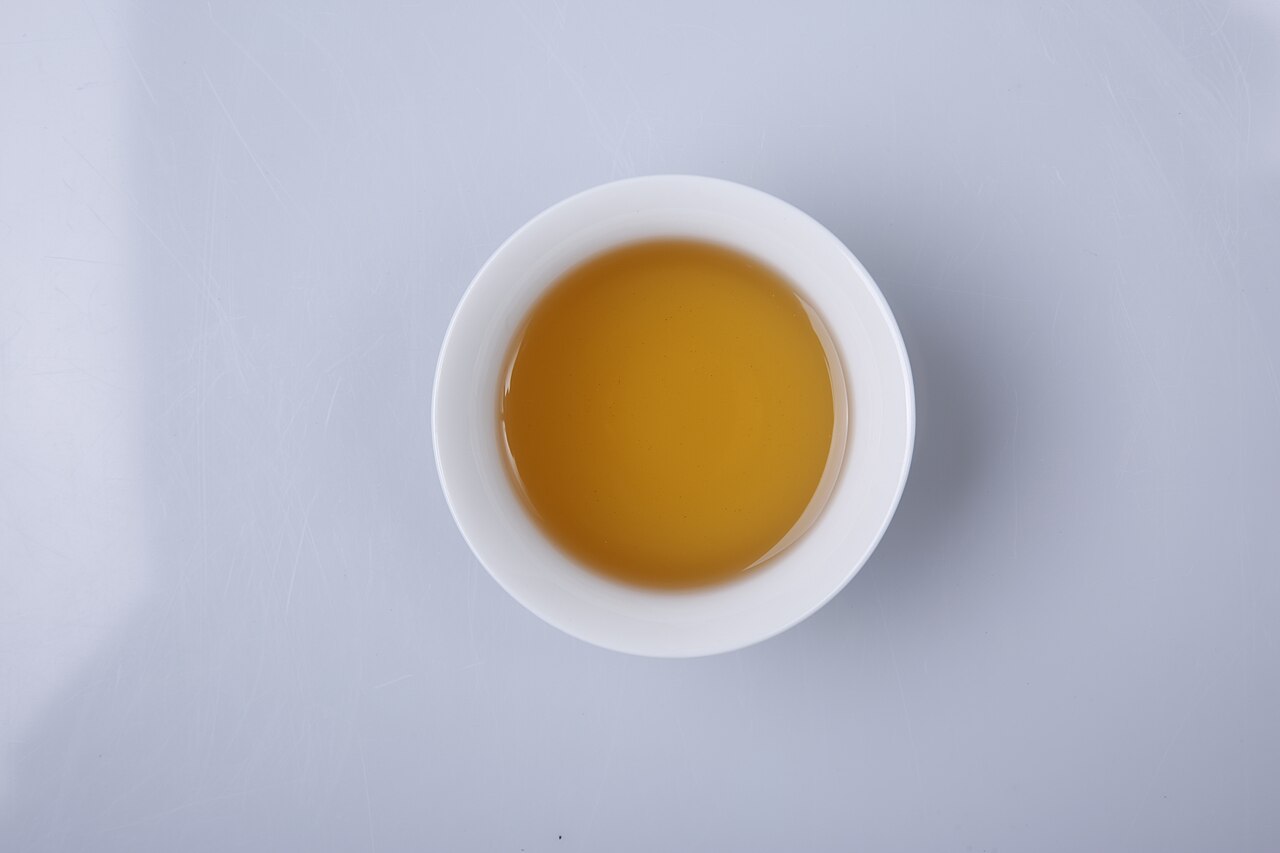 ชาเถาว์ (莓茶 vine tea) ของจางเจียเจี้ยชงเป็นน้ำชาสีเหลืองอำพันใสในถ้วยขาว ชาสมุนไพรประจำเมืองรสหวานอมขมชุ่มคอ