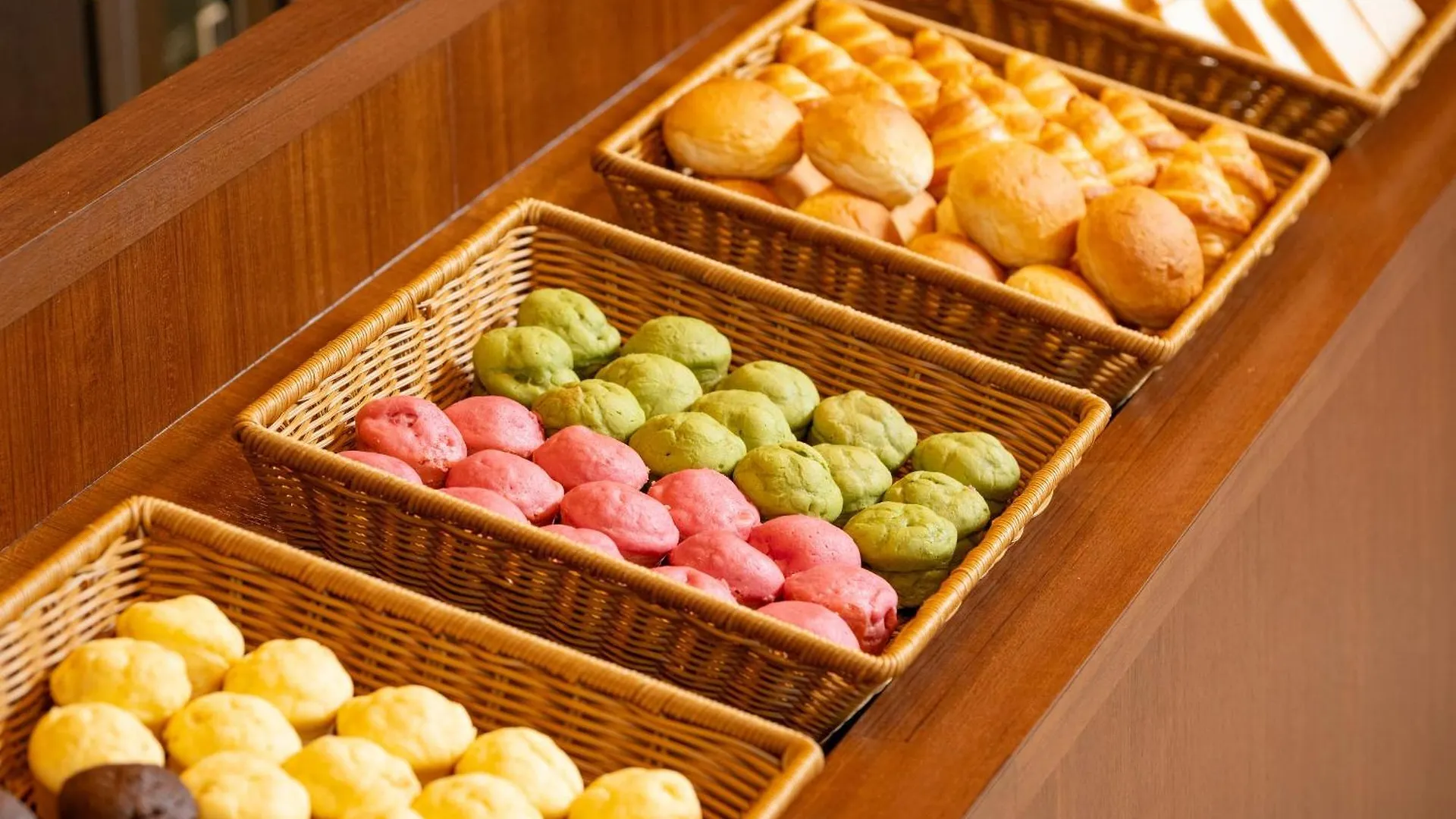 บุฟเฟต์อาหารเช้า APA Hotel Nagoya Sakae — ขนมปังหลากสีในตะกร้าหวาย