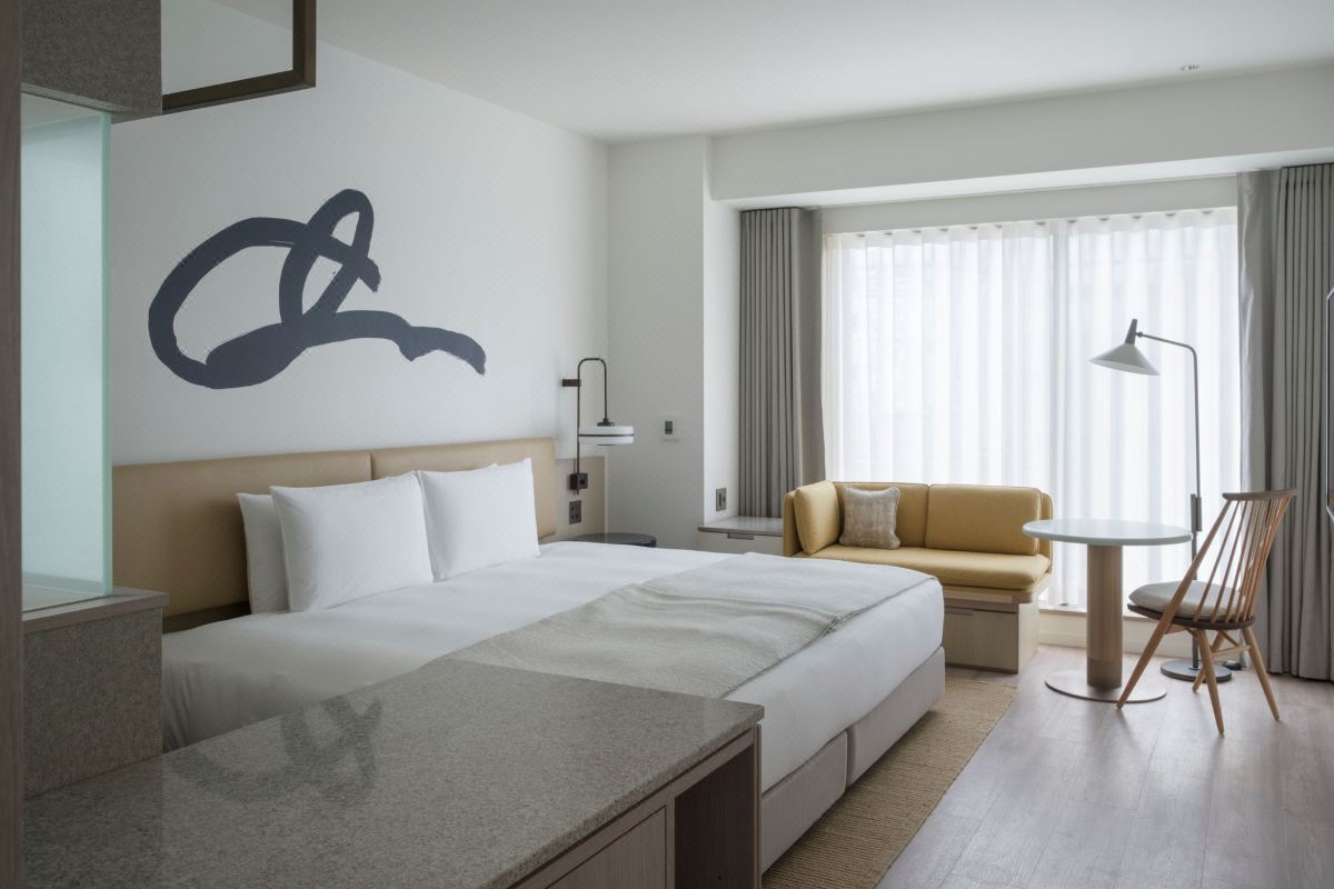 Studio room at Zentis Osaka with a signature ink-brush headboard, mustard sofa and warm wood floor