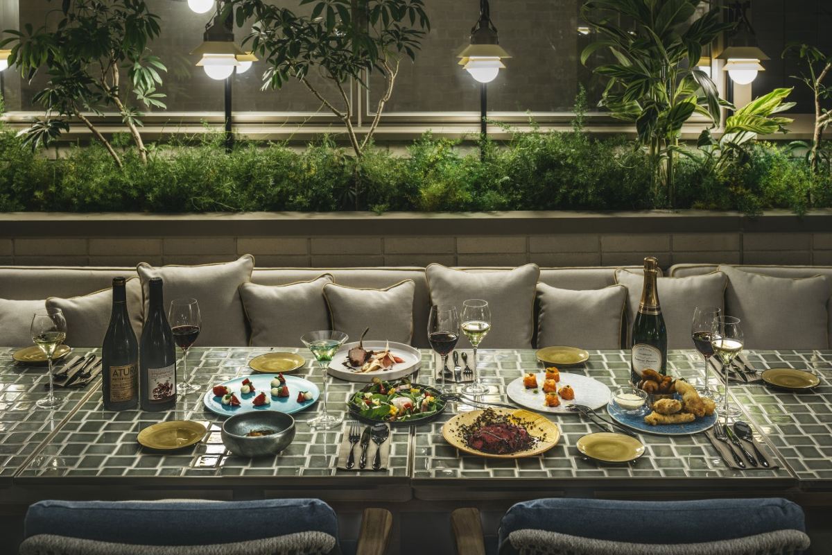 Table set for dinner at UPSTAIRS, the top-floor restaurant, beside a planted terrace banquette