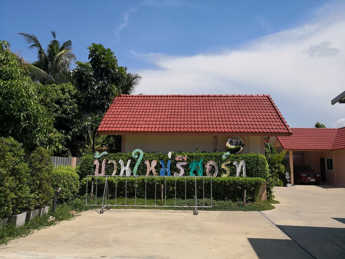 ป้ายทางเข้าบ้านไม้รีสอร์ท บ้านหลังคากระเบื้องแดงกลางสวน