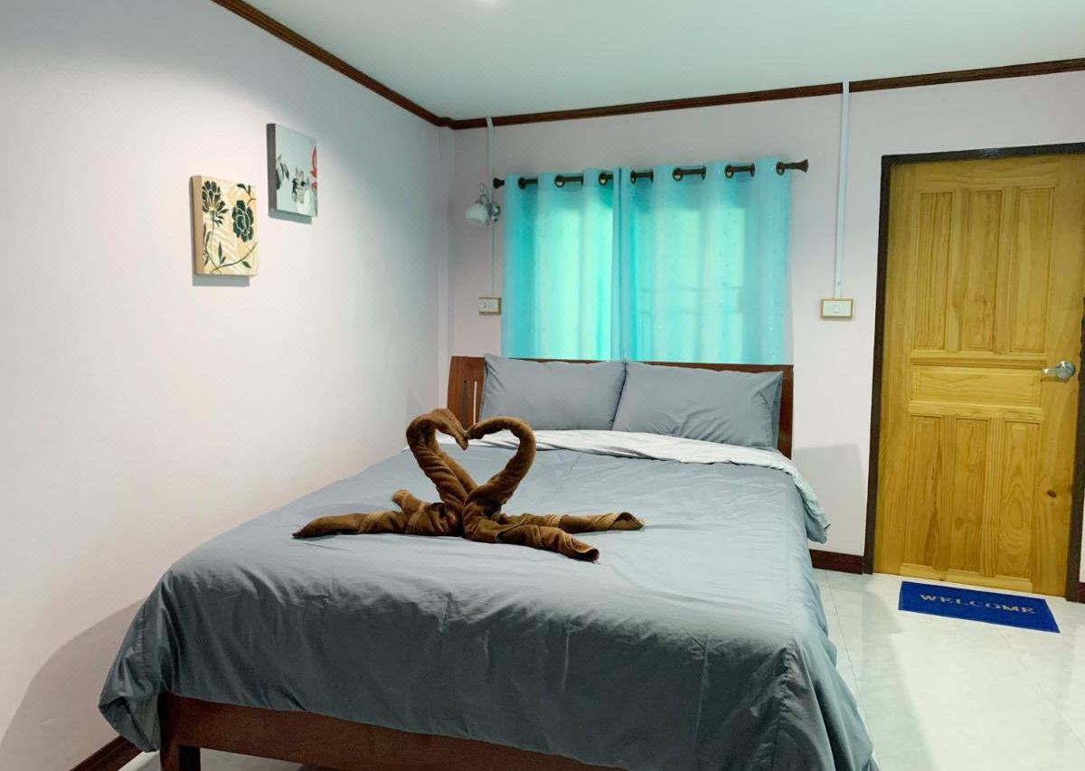 Guest room with a large bed, grey linens, towels folded into swan shapes, and a flat-screen TV