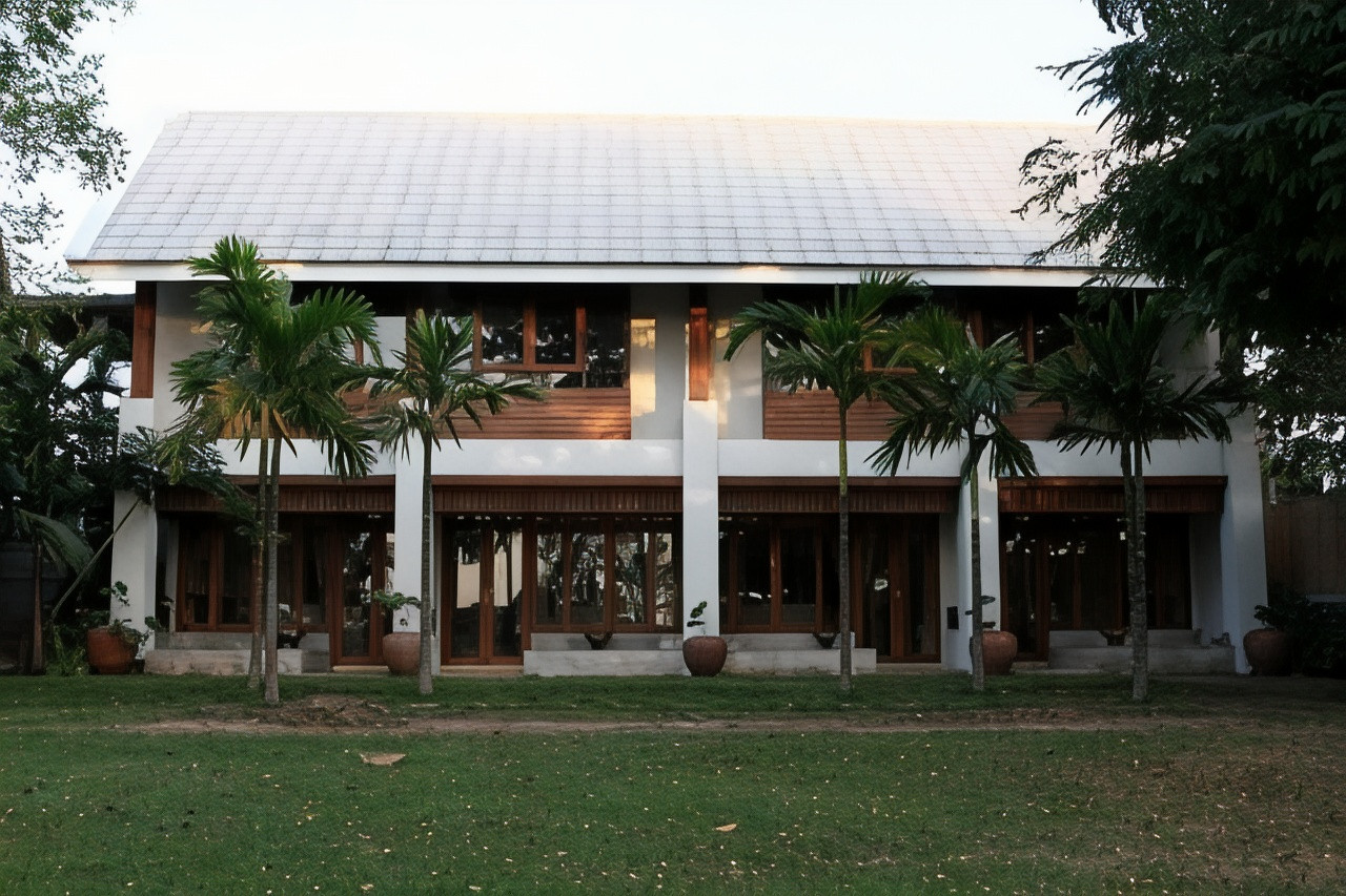 Two-storey teak house with garden and betel-nut palms by day