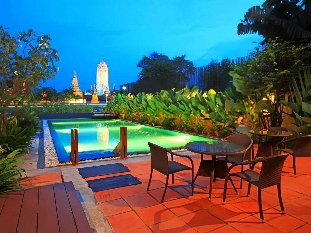 iuDia riverside pool at dusk with a lit temple prang on the far bank of the river