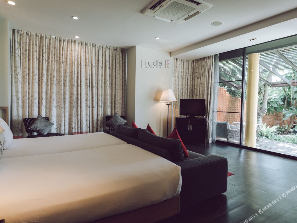 Spacious guest room with dark wood floor, iuDia logo on the wall, opening to a garden terrace